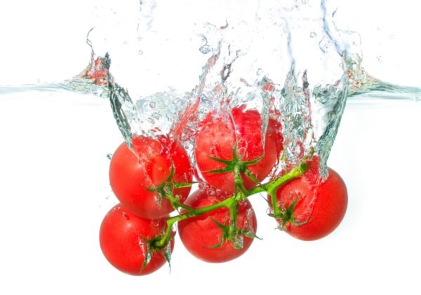 A vine of fresh red tomatoes plunging under water with a big splash and air bubbles