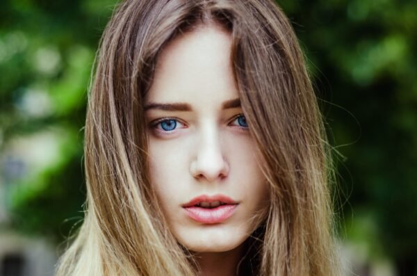 Close-up face portrait of a beautiful young woman with bright blue eyes and long hair