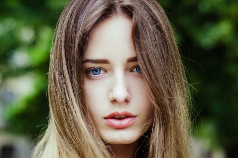 Close-up face portrait of a beautiful young woman with bright blue eyes and long hair